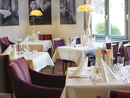 [Translate to english:] Das Göbel's Restaurant Schwanenteich mit eingedeckten Tischen und violetten Stühlen.