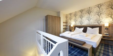 Komfortables Doppelbett aus Holz im Schlafzimmer des Galeriezimmers in Göbel's Seehotel Diemelsee